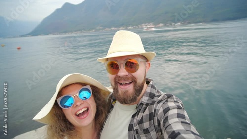 Concept of travel and new experiences. A happy couple takes a selfie against the backdrop of the bay and mountains