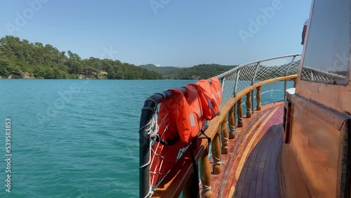 View from the stern of a sailing ship concept, a ship sails on a sea or lake, view from the stern of the ship to aquamarine water closeup concept, mountains in the background  photo