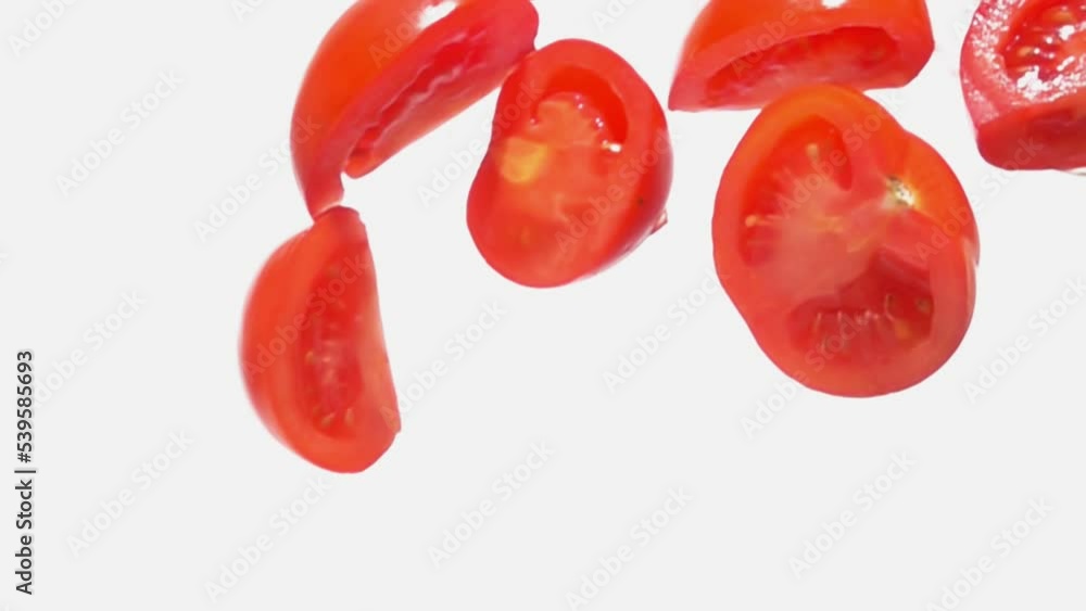 Tomato halves are falling diagonally on a white background in super slow motion Tomato halves are falling diagonally on a white background in super slow motion