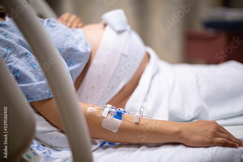 Photo A pregnant woman being monitored in the hospital, connected to a cardiogram and iv