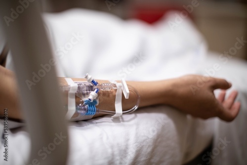 A hospitalized patient lying in in bed in critical condition, connected to an iv drip tube. Sick people in the hospital.
