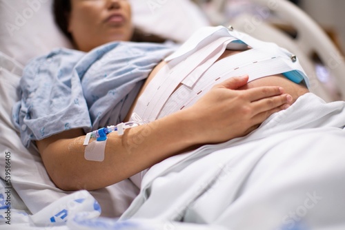 A pregnant woman in the hospital with a iv drip and a cardiograph. Childbirth and labor.