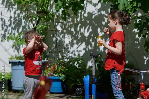 Brother and sister are playing with soap bubbles
