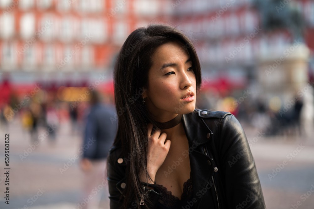 Chinese young and pretty girl in Plaza Mayor of Madrid, Spain, wearing a leather jacket