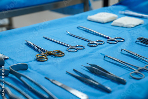 surgical instruments and tools including scalpels, forceps and tweezers arranged on a table for a surgery, Sterilized surgical instruments on the blue wrap
