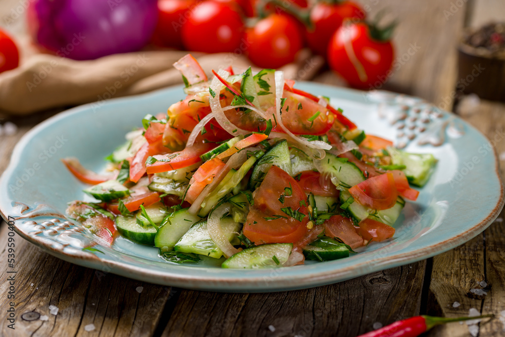 Vegetable salad with tomatoes and cucumbers and red onion on old wooden table Vegetable salad with tomatoes and cucumbers and red onion on old wooden table