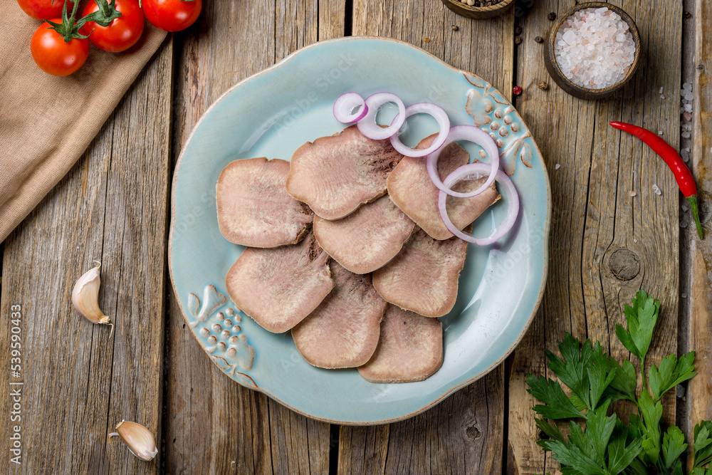 Fototapeta premium Beef tongue with red onion rings on old wooden table top view