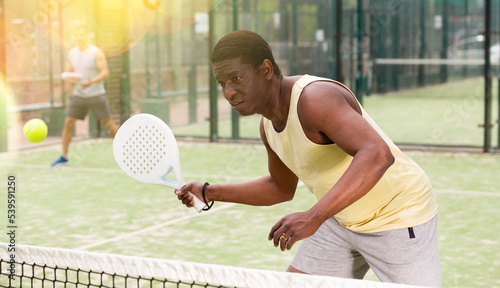 African american man and latino woman playing paddle tennis outdoor © JackF