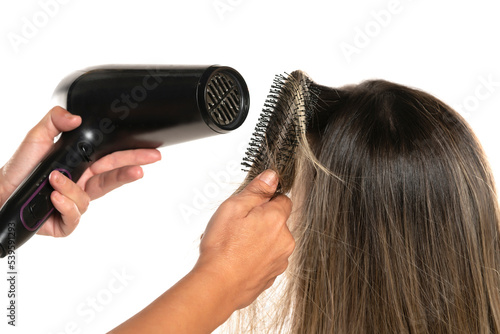 Rear view of a hairdresser drying woman's hair in studio