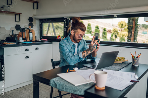 Young business man working at home with laptop and a smartphone
