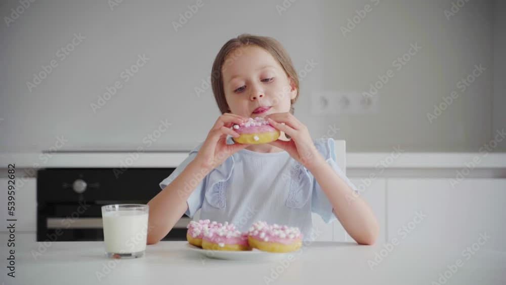 Portrait happy child 6 years old eats an appetizing sweet dessert donut in glaze. Cheerful caucasian little girl eats a sweet donut. Close-up of the mouth of a child eating sweet pastries. 4K Portrait happy child 6 years old eats an appetizing sweet dessert donut in glaze. Cheerful caucasian little girl eats a sweet donut. Close-up of the mouth of a child eating sweet pastries. 4K