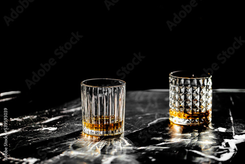 whisky glass drink on a black marble table projecting shadows and black background