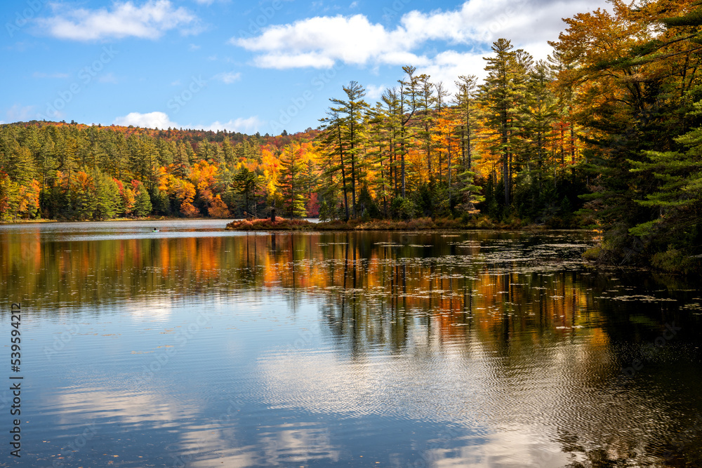 Londonderry, VT - USA - Oct. 8, 2022 Landscape autumnal view of the picturesque 102-acre Lowell Lake, located in Vermont’s Lowell Lake State Park. Red, yellow orange trees reflecting in the water.