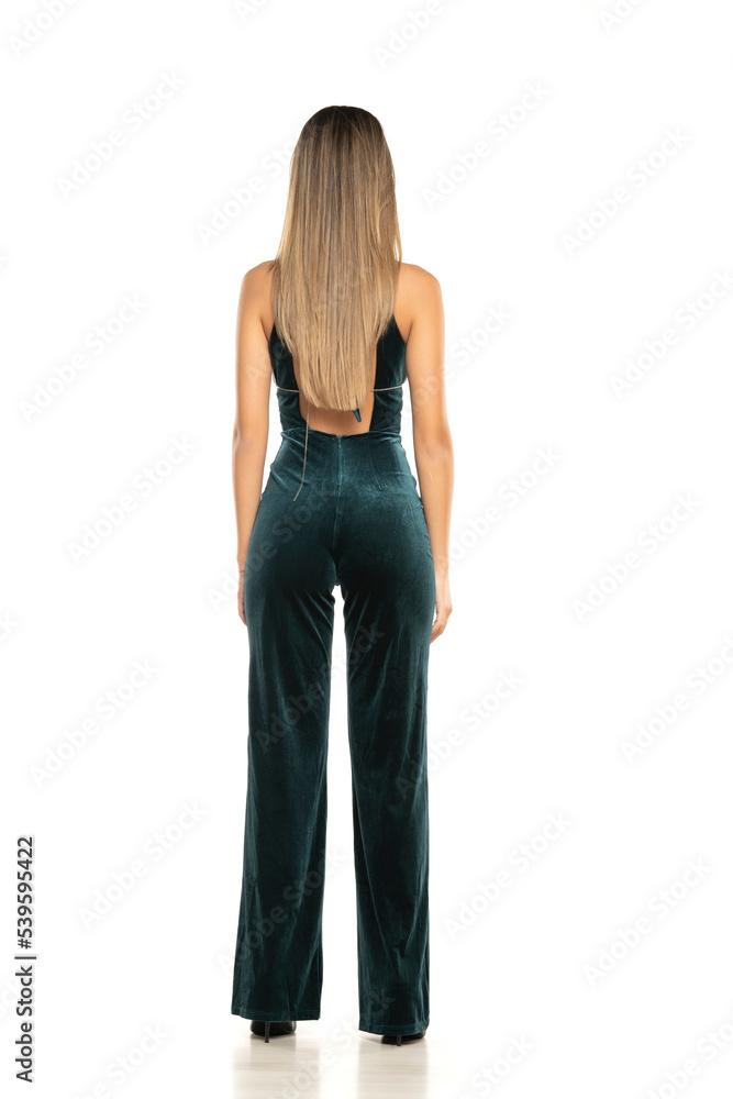 Fototapeta premium Rear view of a fashionable brunette woman with long legs wearing One Piece Jumpsuits trousers,