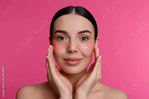 Obraz na plátně Beautiful young woman with under eye patches on pink background