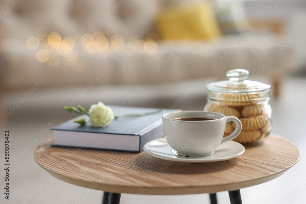 Cup of coffee, cookies, book and eustoma flower on wooden table in living room Cup of coffee, cookies, book and eustoma flower on wooden table in living room