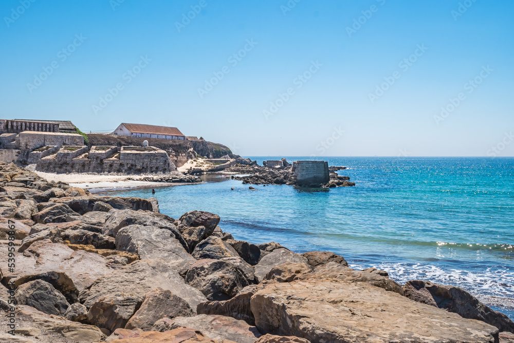 Selective focus in rocks with turquoise Atlantic Ocean and walls of the fort of the island of Las Palomas next to El Foso, Tarifa SPAIN
