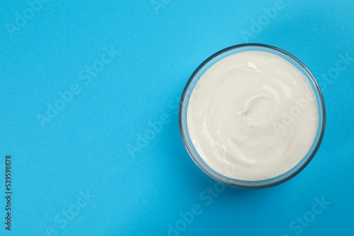 Bowl of tasty organic yogurt on light blue background