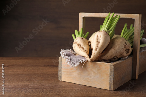 Basket with fresh sugar beets on wooden table. Space for text