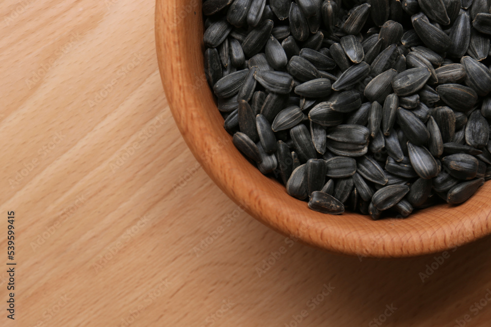 Organic sunflower seeds in bowl on wooden table, top view. Space for text Organic sunflower seeds in bowl on wooden table, top view. Space for text