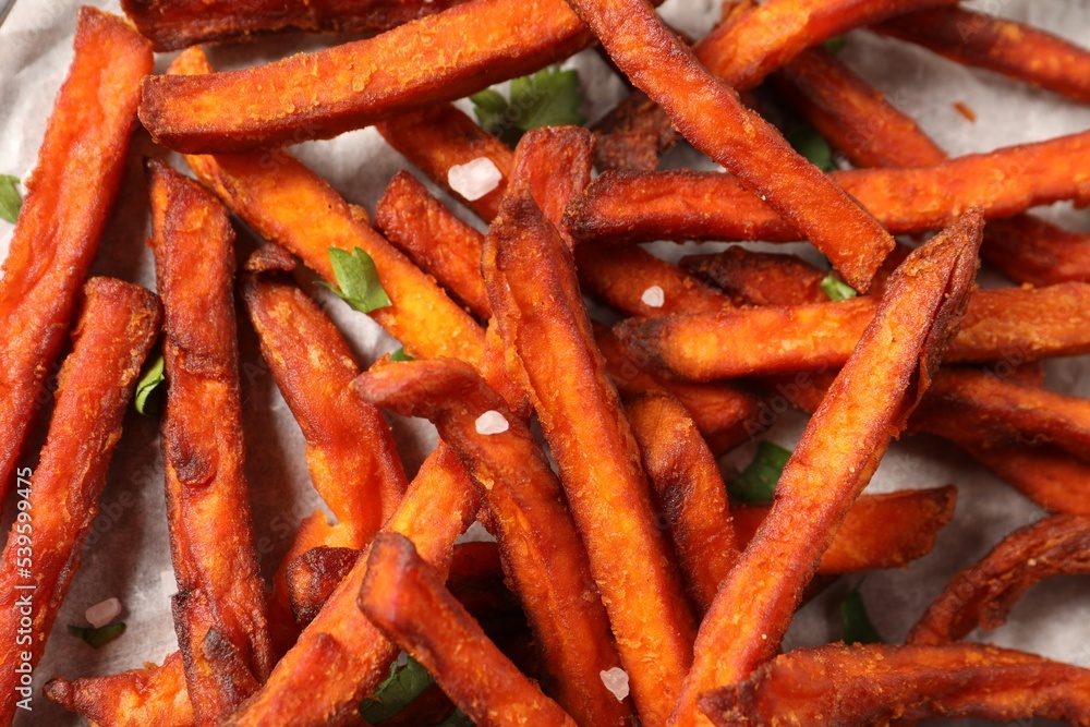 Delicious sweet potato fries on parchment paper, closeup Delicious sweet potato fries on parchment paper, closeup