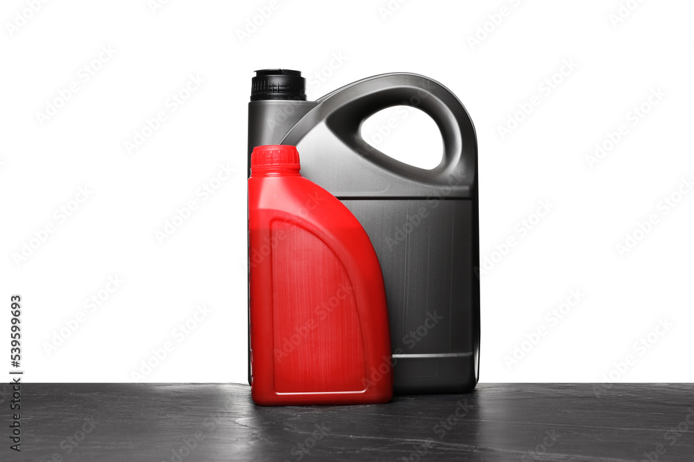 Motor oil in different canisters on black table against white background Motor oil in different canisters on black table against white background
