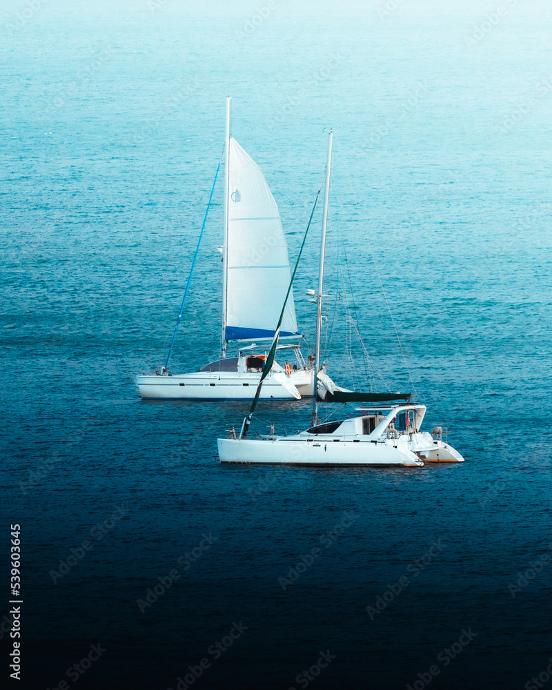 Fototapeta premium Two boats sailing away from old of san juan puerto rico with the amazing deep blues of the ocean
