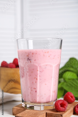 Tasty raspberry smoothie in glass on white table, closeup
