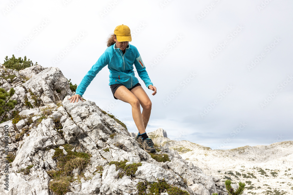 Woman Hiker Moving Carefully Down from Mountain Top