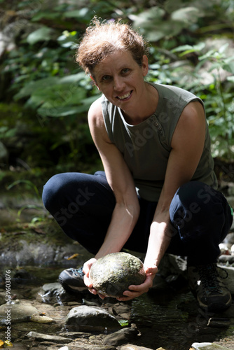 Mid Adult Woman Holding a Spherical Stone Found in a Forest Water Stream Looking at Camera