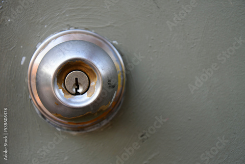 A close up image of the key hole on an old weather worn metal door knob.