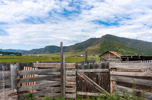 View of small mountains from the side of wooden rural outbuildings in the Republic of Gorny Altai