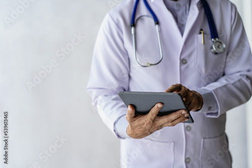 Male doctor talks to patients online via video call via webcam on computer, laptop, smartphone, tablet. Teleconference is like a teleconference.