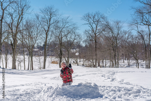 The boy plays with snowballs in the snow