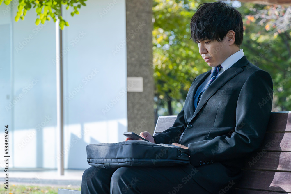ベンチに座り休憩するビジネスマン ベンチに座り休憩するビジネスマン