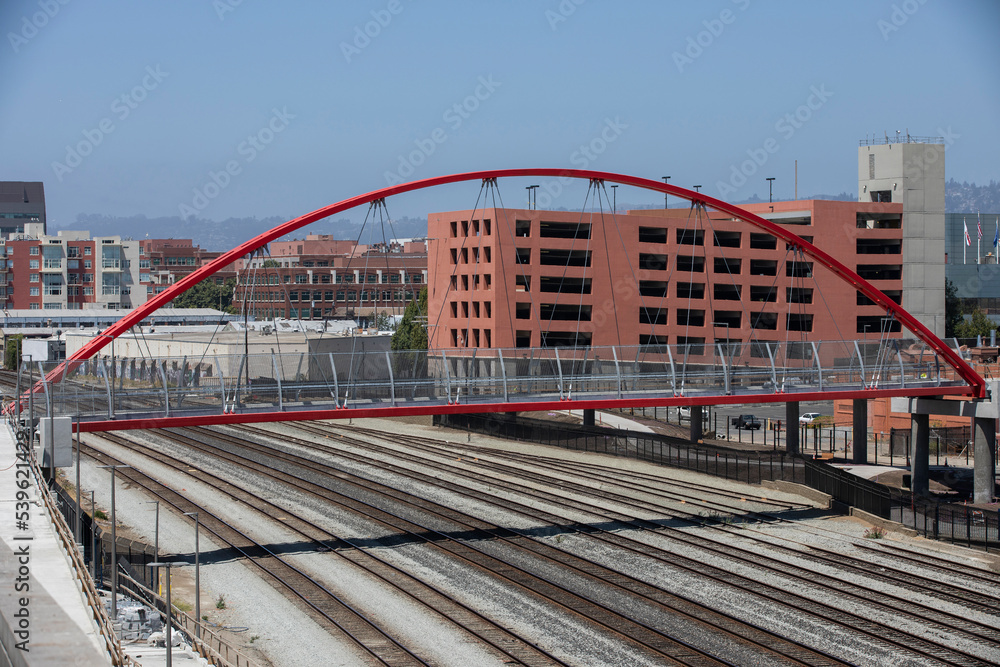 A bridge crosses train tracks in downtown Emeryville, California, USA. - obrazy, fototapety, plakaty 