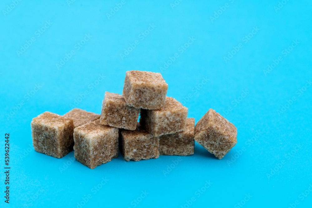 pile of brown sugar cube on blue background pile of brown sugar cube on blue background
