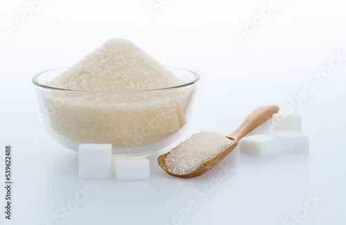A bowl granulated sugar and sugar cubes on white background