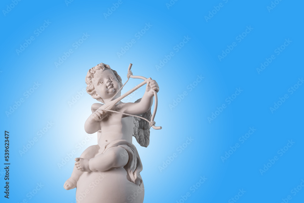 Figurine of an angel Cupid on the podium with a bow and arrow on a blu background . Valentine's Day.Place for text. - obrazy, fototapety, plakaty 