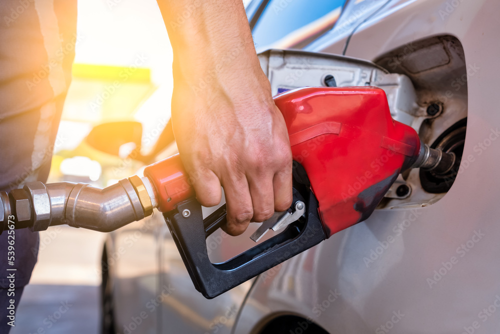 Closeup of a hand man pumping petrol in car at refueling station - Transport and ownership concept. Closeup of a hand man pumping petrol in car at refueling station - Transport and ownership concept.