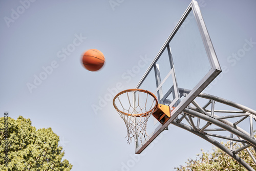 Basketball net, ball and outdoor sports goals, competition game and action on sky background. Background basketball court, shooting hoops and winning target, training skill and fun performance in air © Beaunitta V W/peopleimages.com