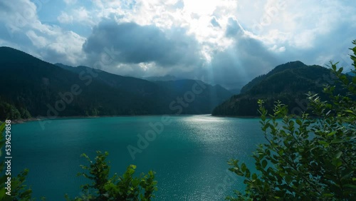 Time lapse of dramatic clouds in front of sun over Sauris Lake (Lago di Sauris) in Friuli Venezia Giulia, Udine, Italy photo