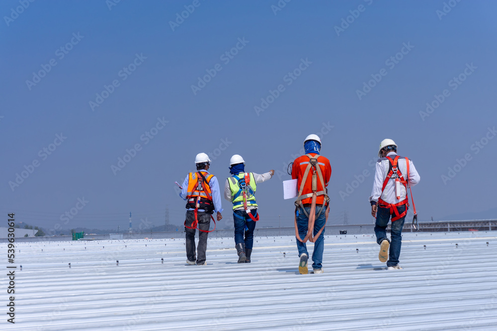 Team engineers wearing full safety body harness working on roof top for