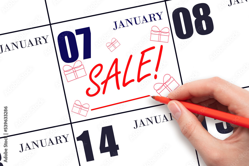Hand writing text SALE and drawing gift boxes on calendar date January 7. Shopping Reminder Hand writing text SALE and drawing gift boxes on calendar date January 7. Shopping Reminder