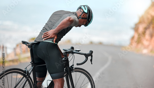 Fototapeta Naklejka Na Ścianę i Meble -  Fitness, sports injury and back pain by man cyclist feel uncomfortable while cycling along mountain route. Training, pain and injured athletic guy suffering from joint, muscle and spinal discomfort