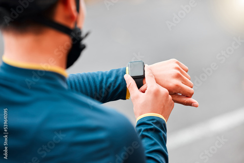 Watch  fitness and man doing a workout  exercise or outdoor cardio in the city road for motivation. Hands of an athlete with monitor of time during training with sports technology in the street
