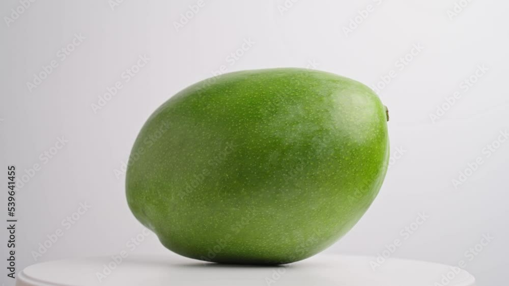 Ripe juicy sweet whole mango rotate on white background close-up. Summer tropical fruit, healthy food, mango juice, organic mango. Mango in green skin. 4K footage Ripe juicy sweet whole mango rotate on white background close-up. Summer tropical fruit, healthy food, mango juice, organic mango. Mango in green skin. 4K footage