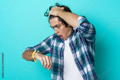 Photography Late for a meeting, shocked at the time young man is gasping, teal studio backgr