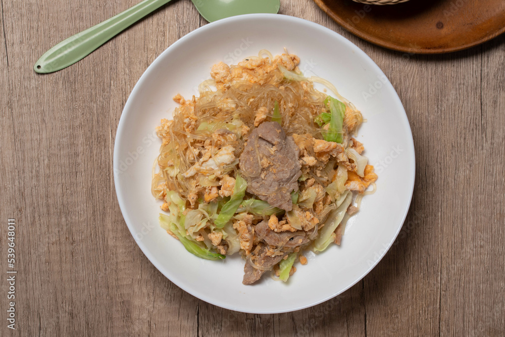 Stir fried vermicelli with pork, egg and collard greens in a white plate. Stir fried vermicelli with pork, egg and collard greens in a white plate.