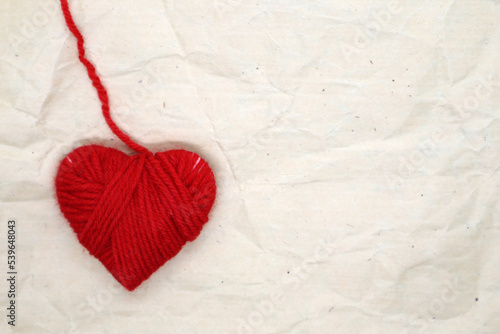 Heart made of red yarn on a beige background. Valentine's day concept.